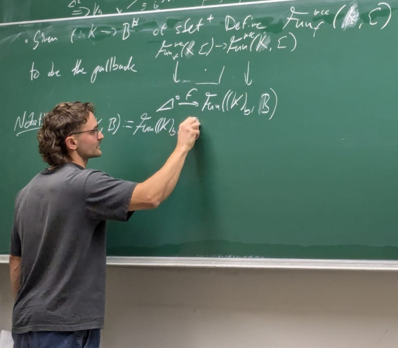 LS giving a talk on the blackboard about Lurie's Straightening-Unstraightening Equivalence at LMU.